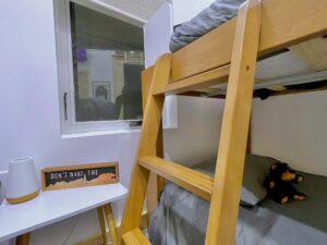 Cozy Red River Gorge cabin bunk bed with a "Don't Wake the Bear" sign on the white desk beside it. Natural light streams through the window, offering a relaxing vacation vibe.