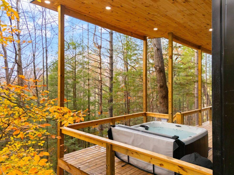 Hot tub on a cabin deck in Red River Gorge, Kentucky, surrounded by fall foliage and forest views. Enjoy relaxing rentals with nature's beauty.