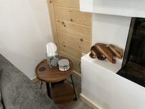 Cozy living room corner with side table, tissues, coasters, and wooden bear decor.
