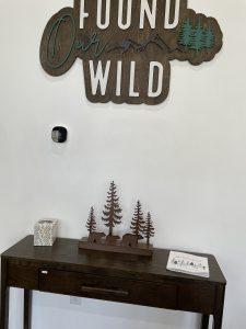 Rustic decor: "Found Our Wild" sign, trees, and dark wood console table.